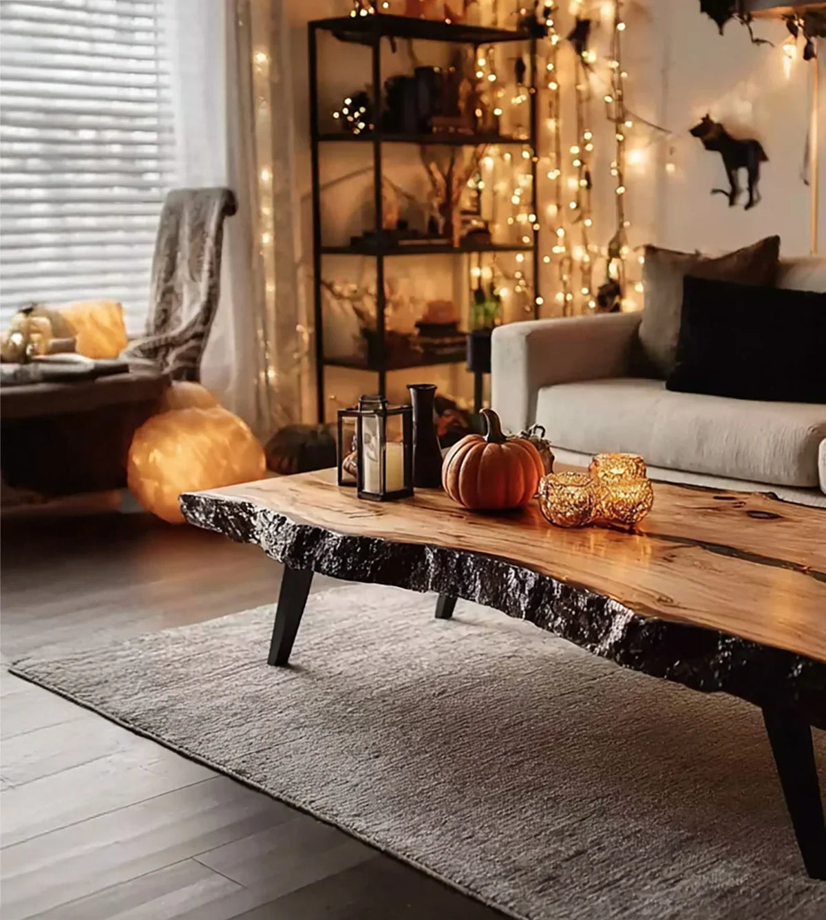 Cozy living room with natural edge wood coffee table decorated with candle holders and pumpkin, warm string lights