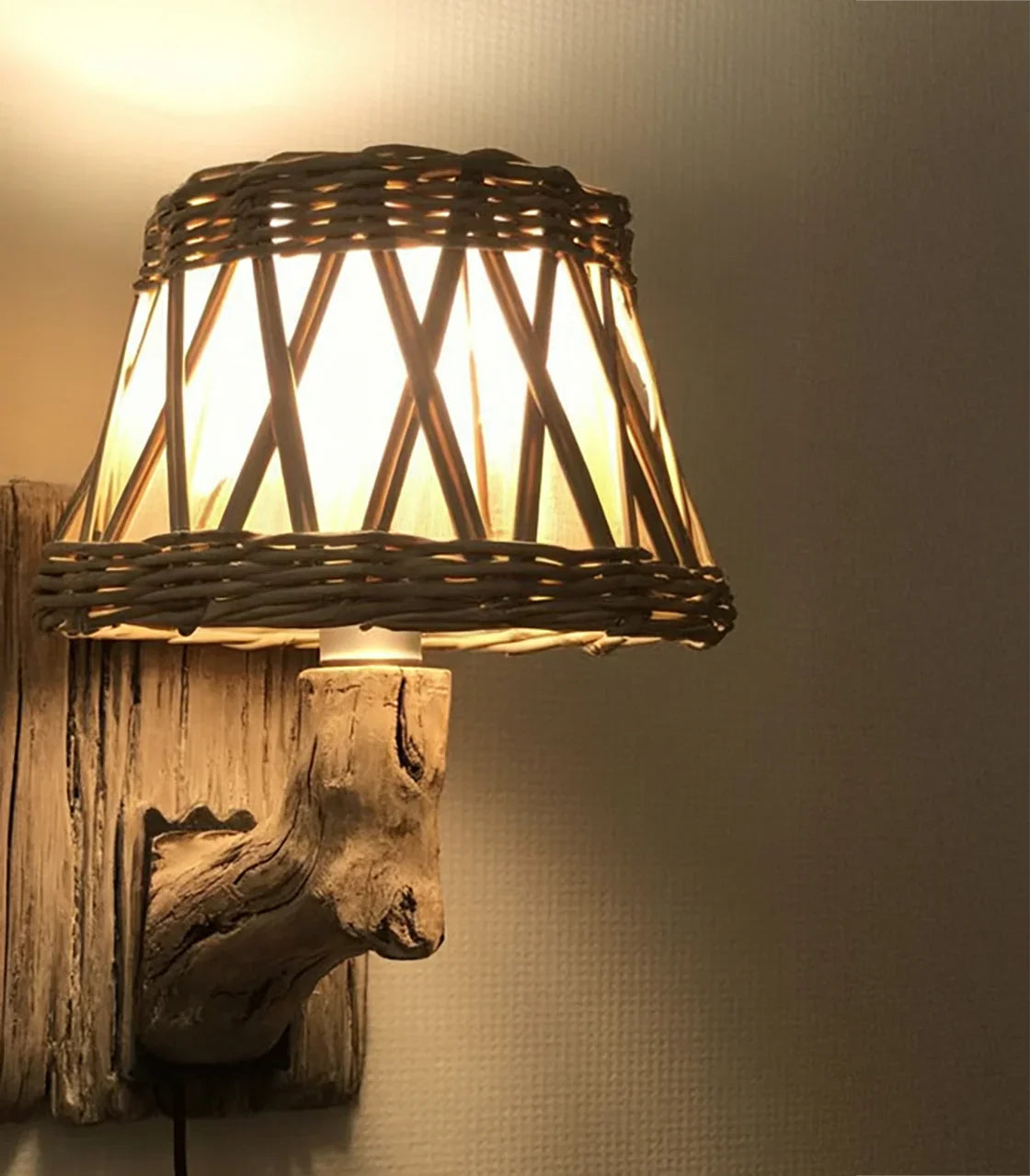 Rustic wall lamp with woven wicker shade and driftwood mount illuminating a textured wall