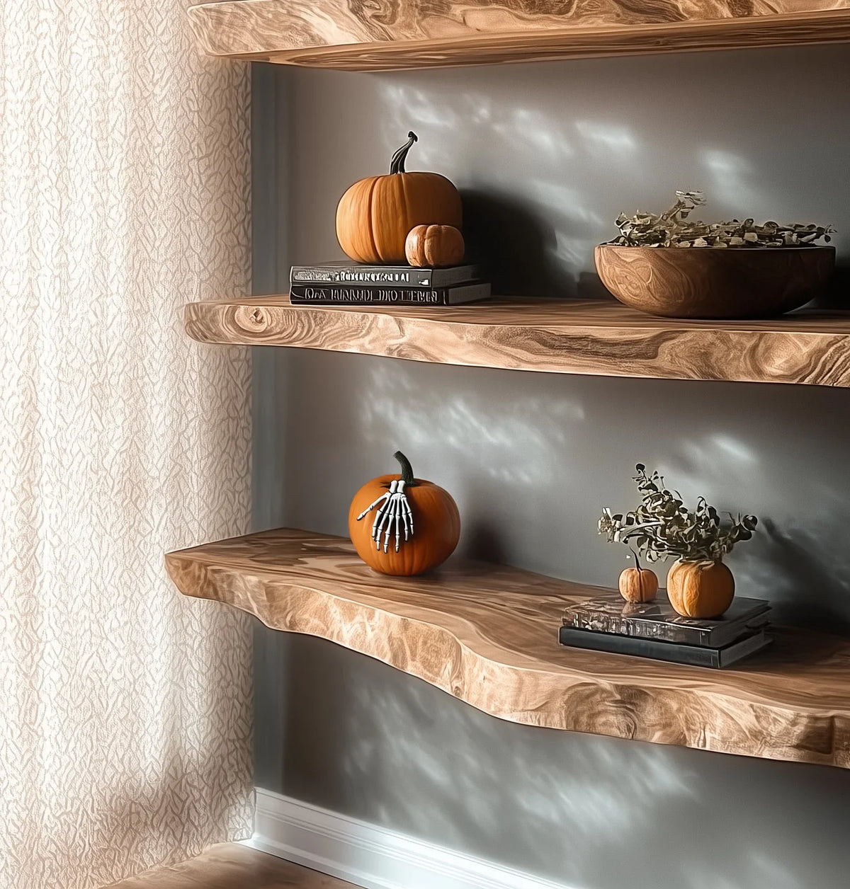Decorative wooden shelves with pumpkins, skeleton hand on pumpkin, books, and dried floral bowl in cozy room