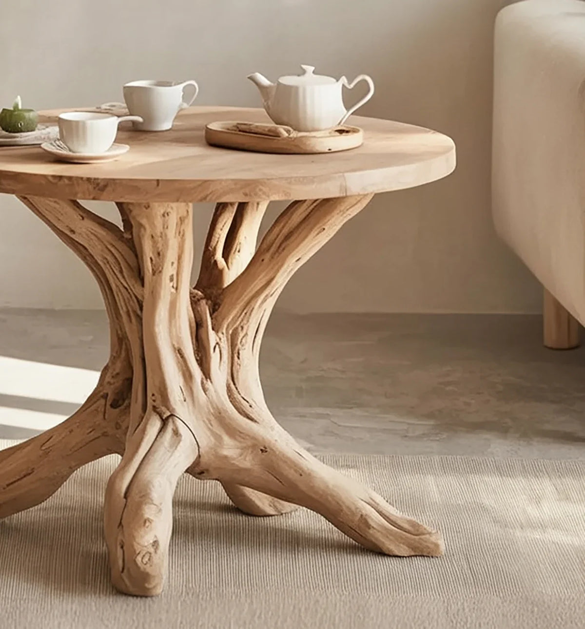 Live edge round wooden coffee table with natural tree trunk base, teapot and cups in modern living room
