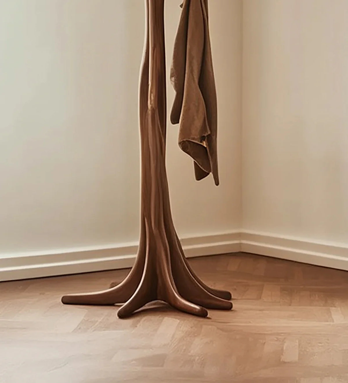 Solid wood tree-inspired coat rack with curved base in a modern interior corner