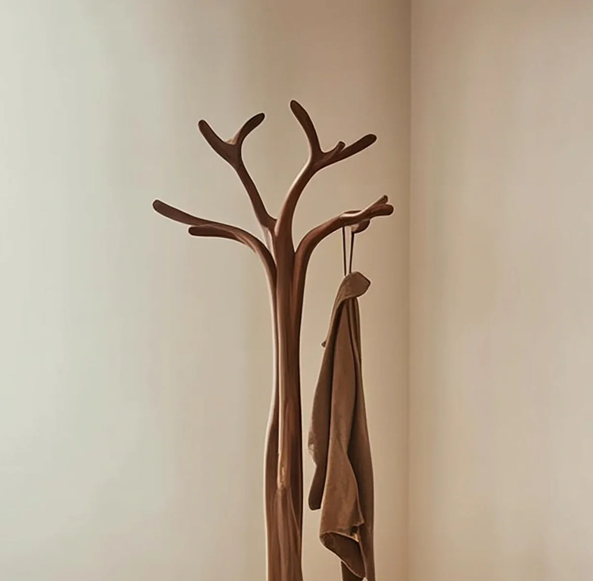 Solid wood tree branch coat rack in minimalist room with hanging brown jacket