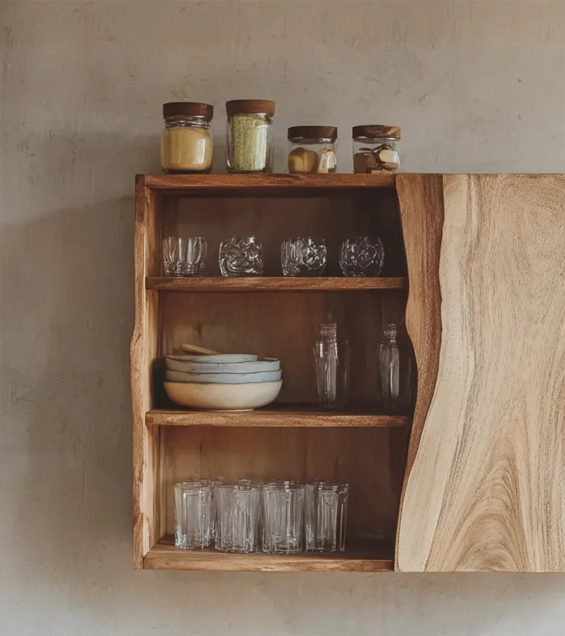 Open wooden wall cabinet with glass jars, bowls, and drinking glasses on shelves