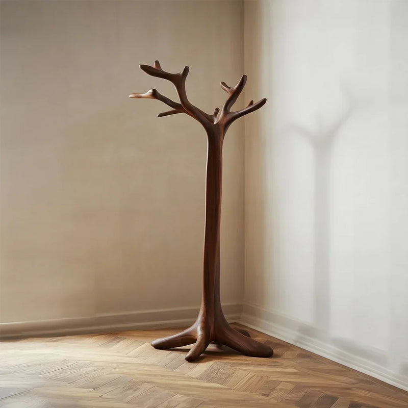 Solid wood coat rack shaped like a tree, standing in a minimalist room with wood flooring.