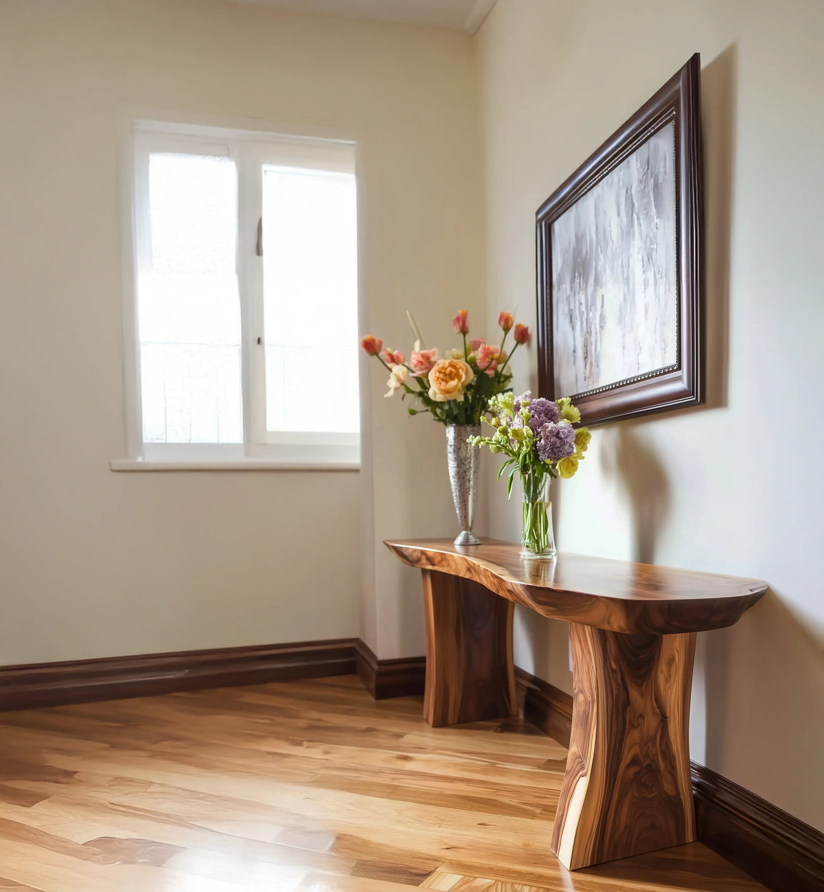 Wooden console table with fresh flower vases under framed painting in bright room