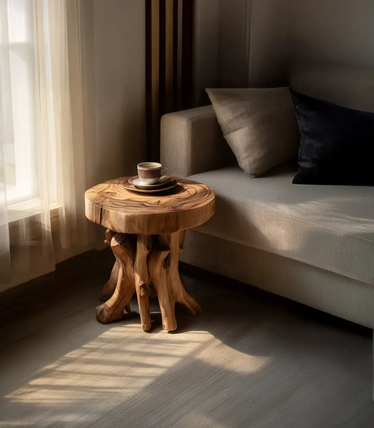 Live edge solid wood side table with unique tree root base beside a modern sofa in sunlight.