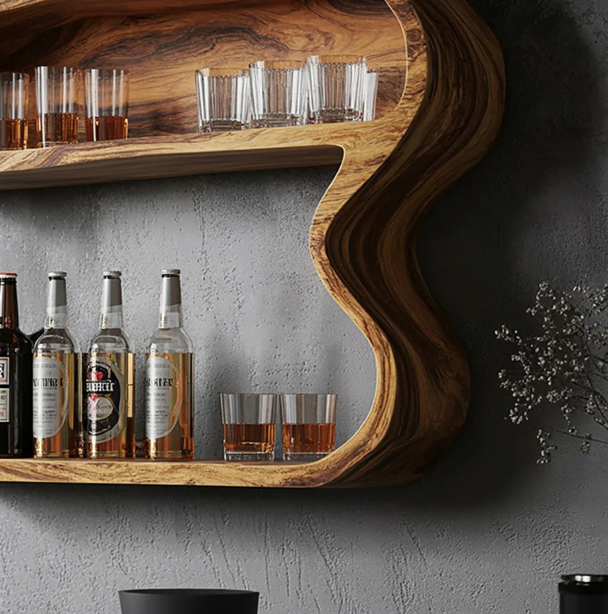 Curved wooden wall shelf holding bottles and whiskey glasses against textured gray wall