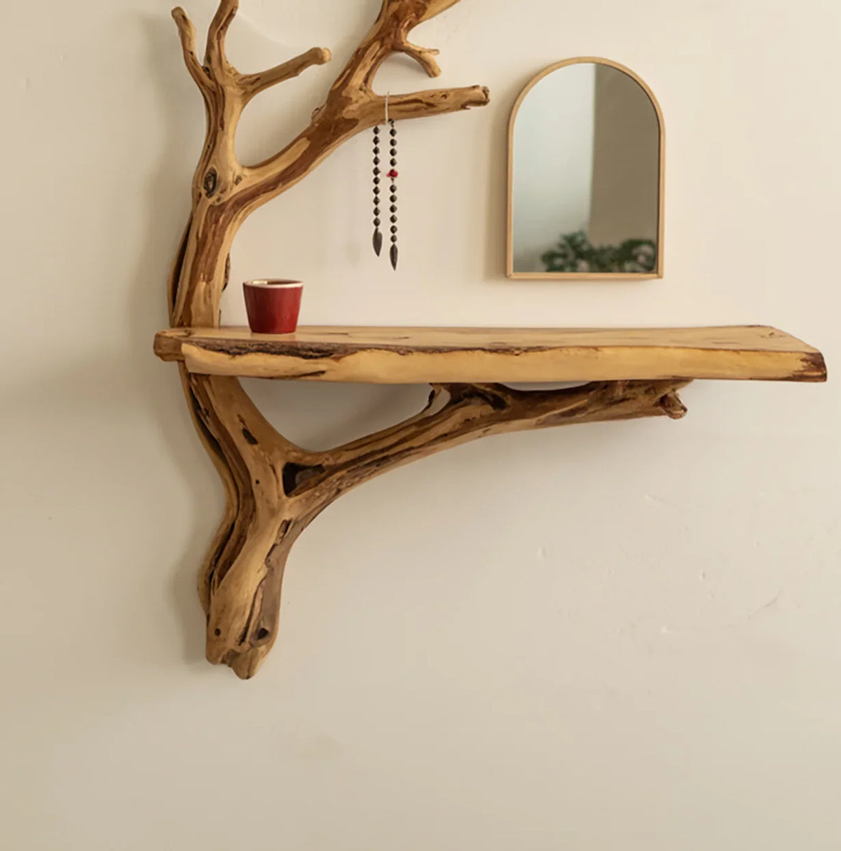 Live edge wood floating shelf with tree branch design, hanging beads, and red cup in minimalist room