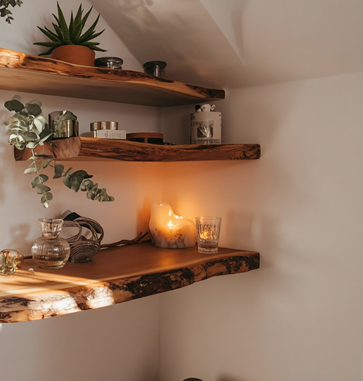 Live edge wooden floating shelves with plants, candles, decor, and soft ambient lighting.