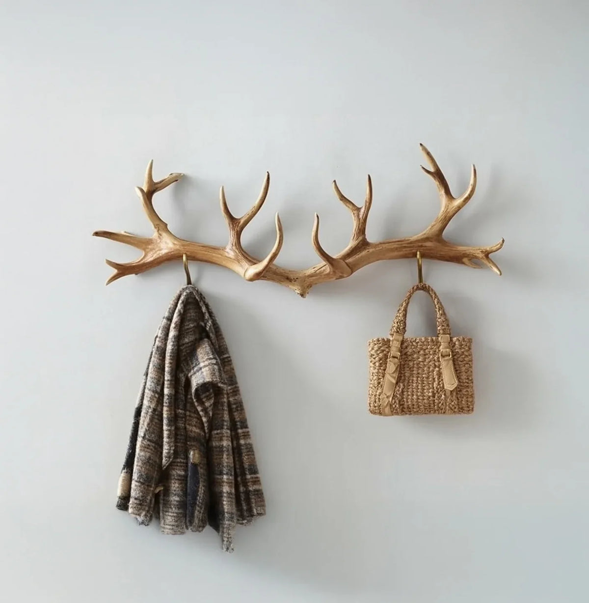 Antler-shaped wooden wall hook rack with a plaid coat and woven bag hanging