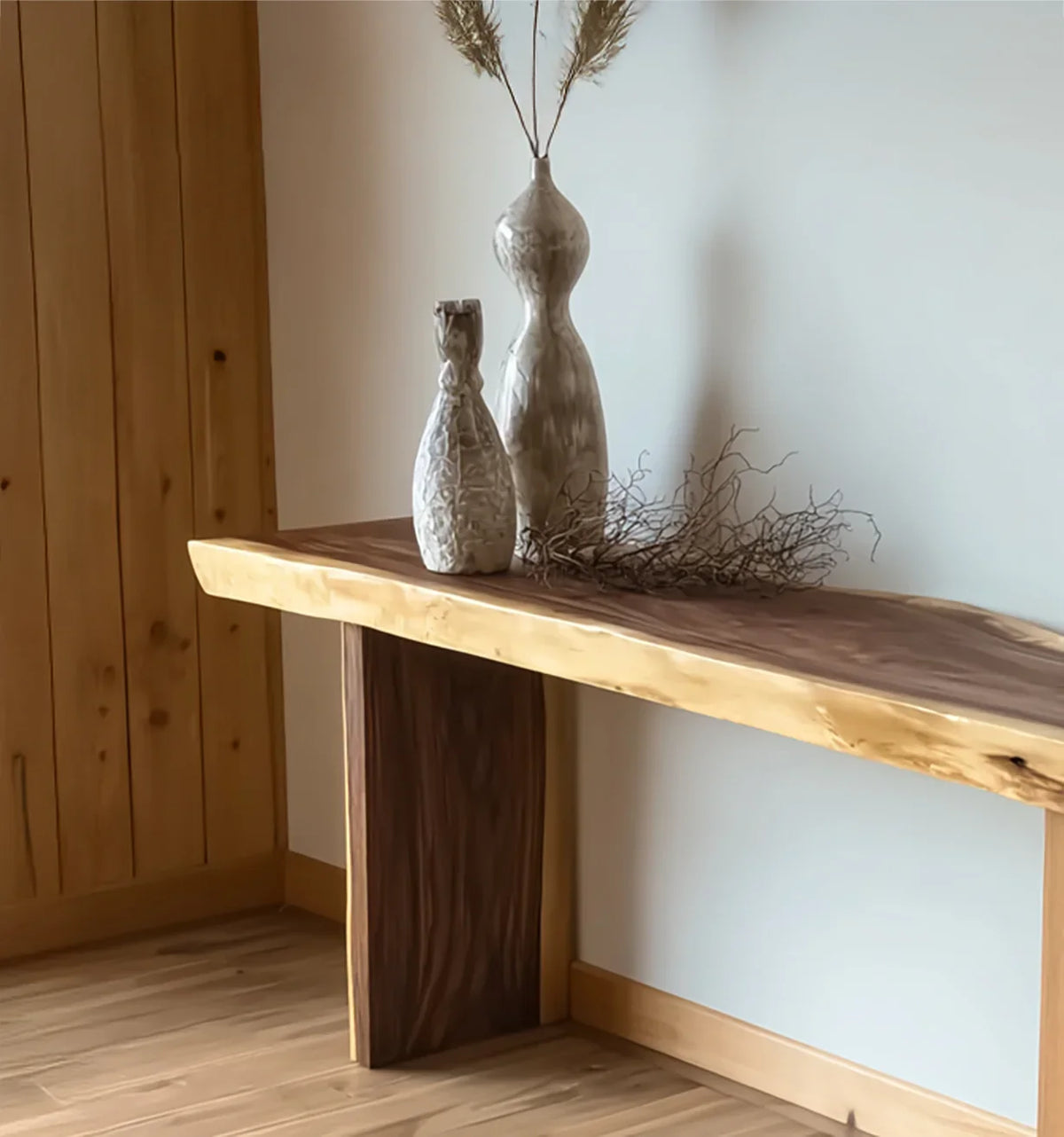 Live edge solid wood console table with decorative ceramic vases in a modern room