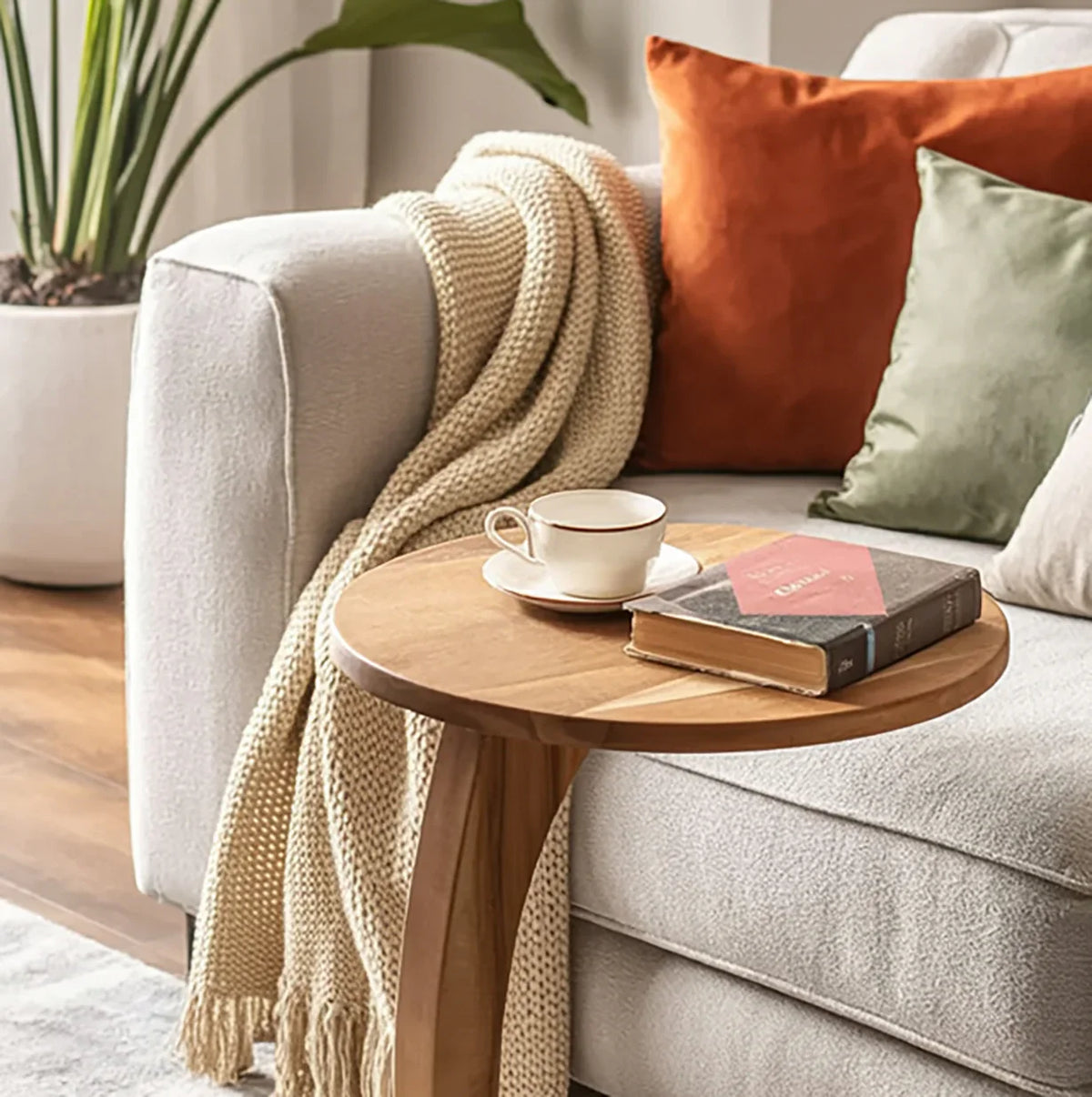 Modern solid wood side table beside sofa with cozy throw, decorative pillows, book, and teacup