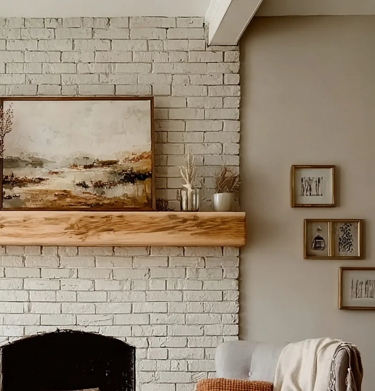 Cozy living room corner with white brick fireplace, wooden mantel, abstract painting, and framed wall art