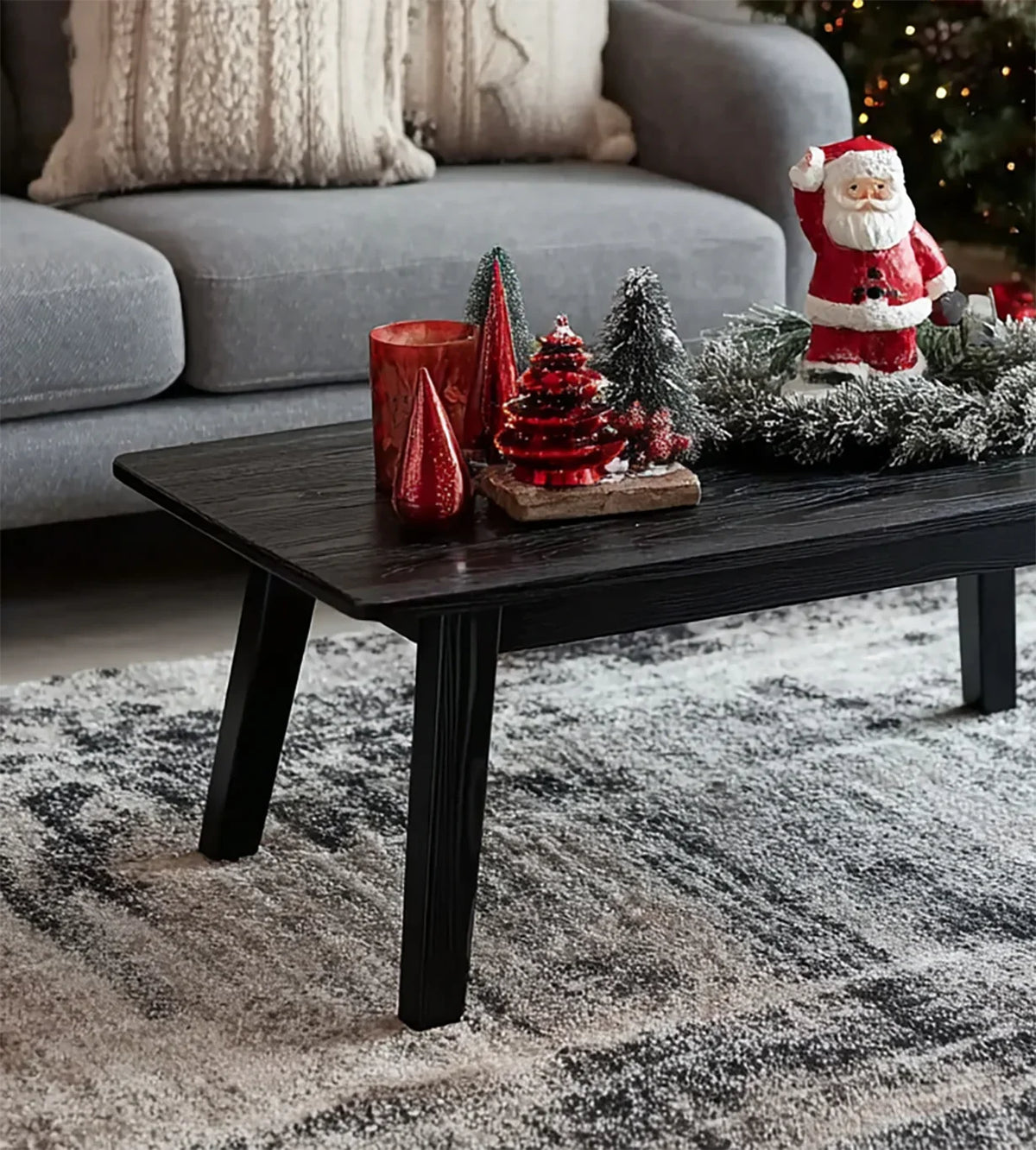 Black wooden coffee table with Christmas decorations including Santa figurine and small trees