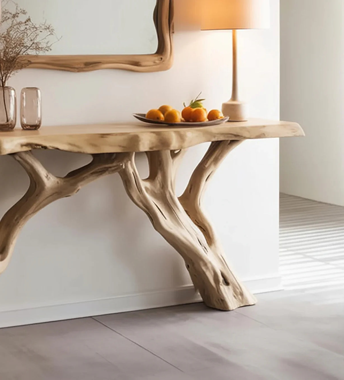 Live edge wood console table with tree branch legs, styled with a lamp and fruit bowl