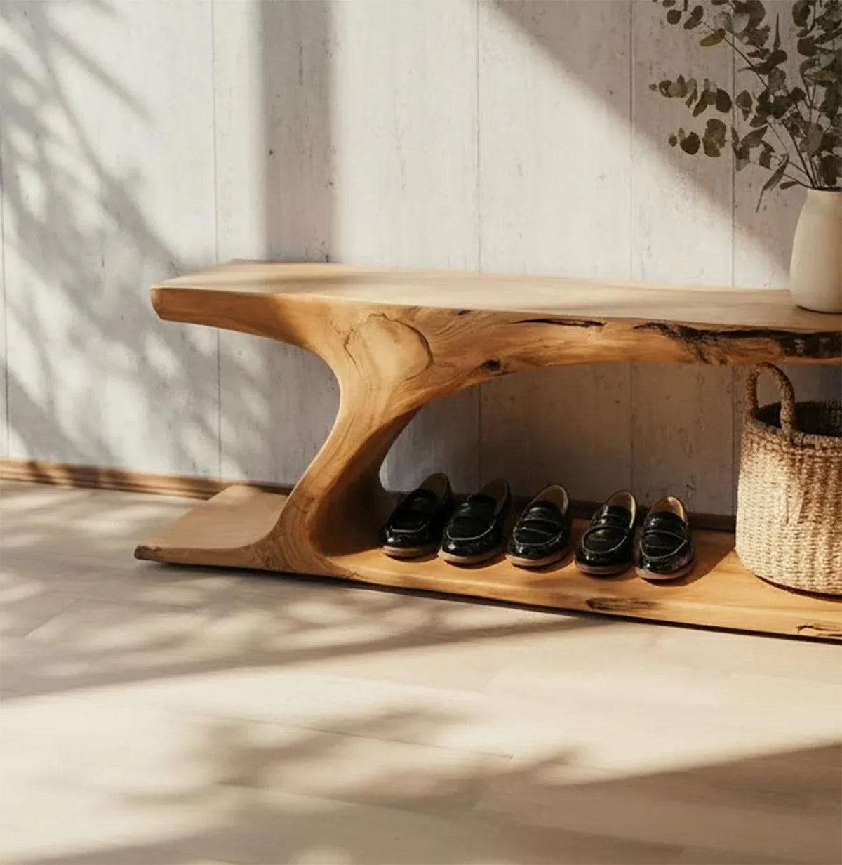 Live edge solid wood bench with sculpted design, shoes underneath, and decorative vase