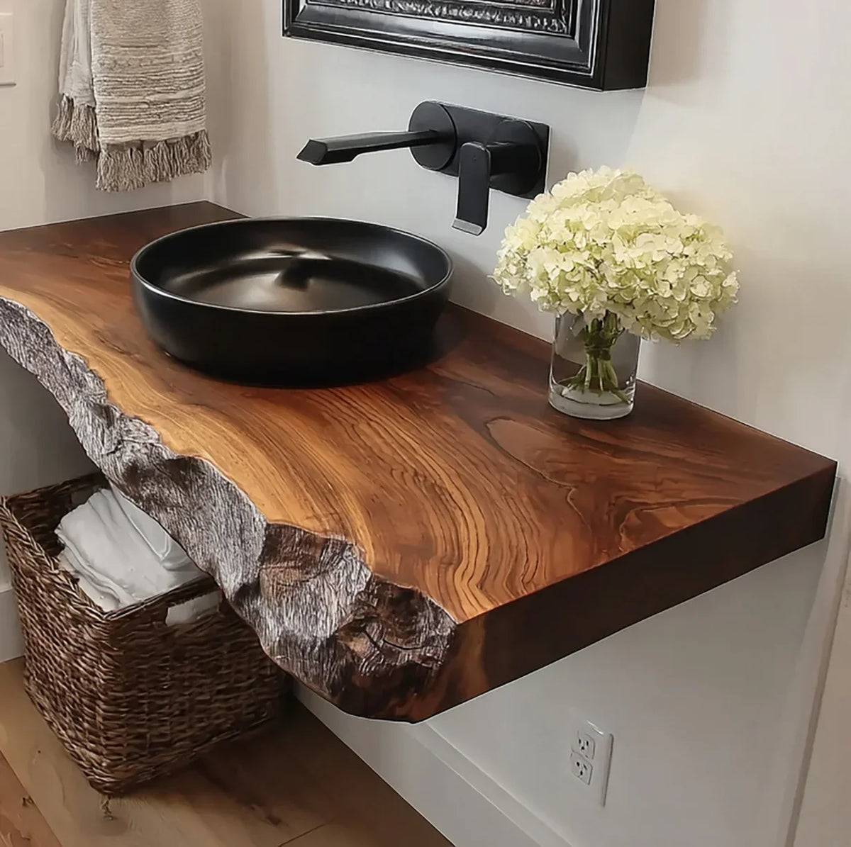 Bathroom vanity with live edge wood countertop, black vessel sink, wall faucet, and white hydrangea bouquet