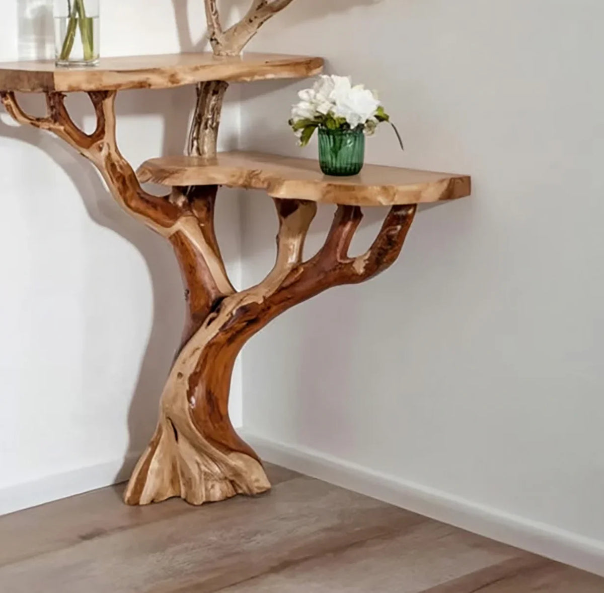 Live edge solid wood tree bookshelf with branching shelves and vase decor, against wall