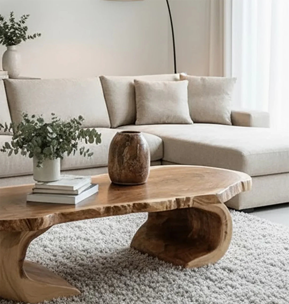 Modern living room with beige sectional sofa, natural wood coffee table, vase, and green foliage
