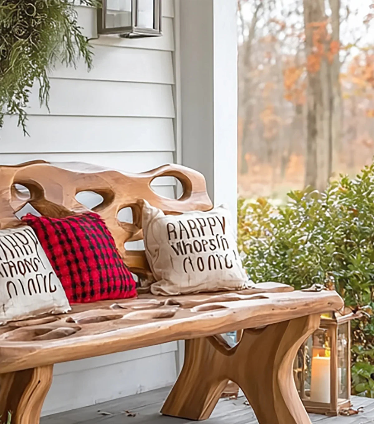 Wooden outdoor bench with decorative throw pillows on a porch surrounded by greenery