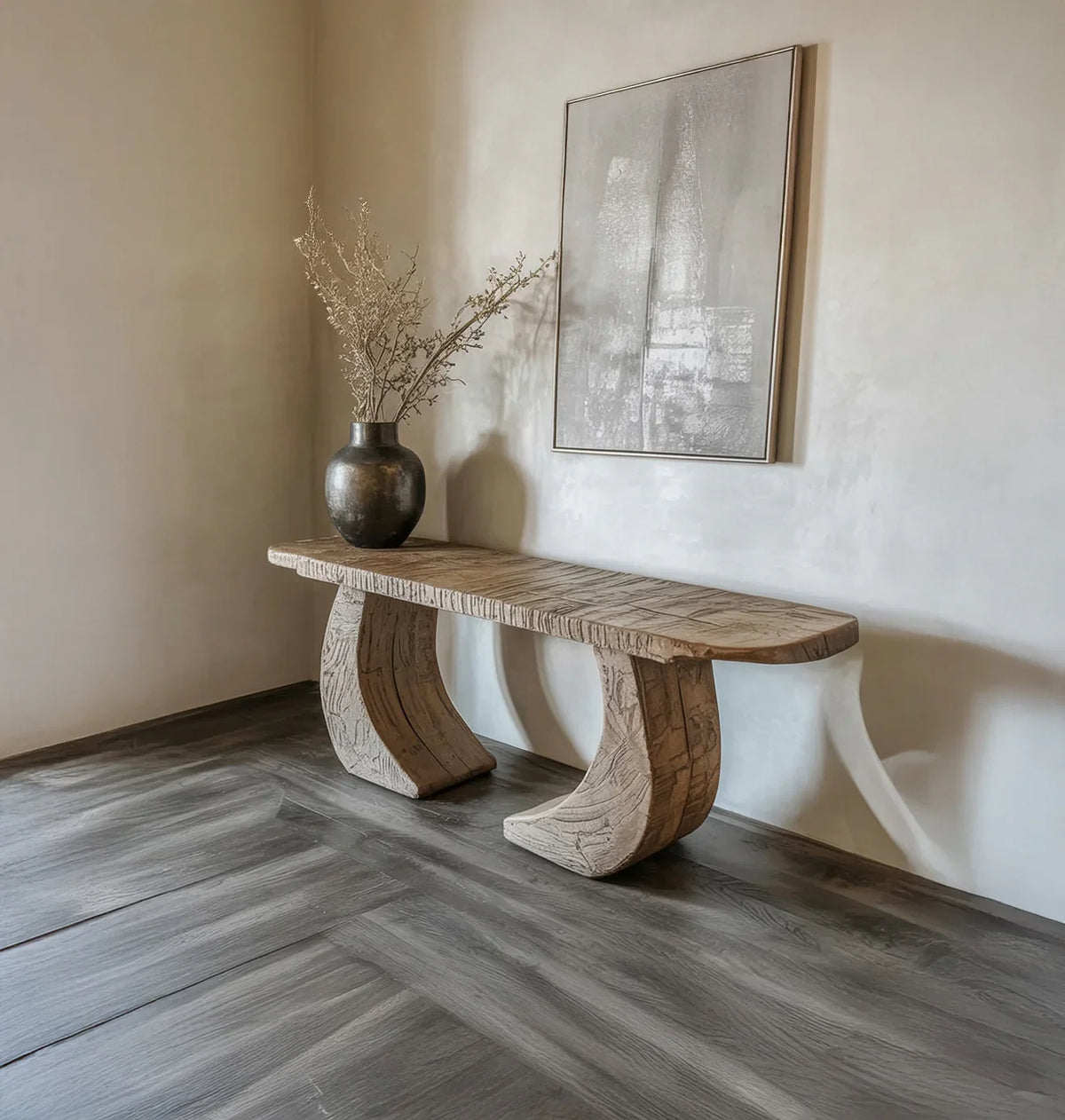Minimalist interior with carved wooden bench, dark vase with dried branches, and abstract wall art