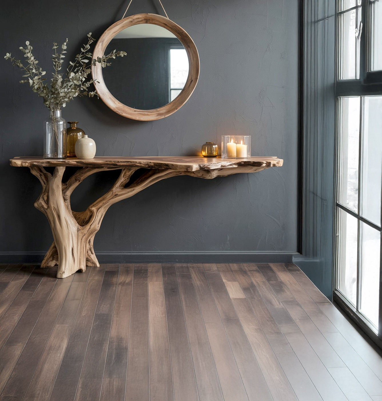 Natural wood console table with decorative candles and vases under round wooden mirror on gray wall