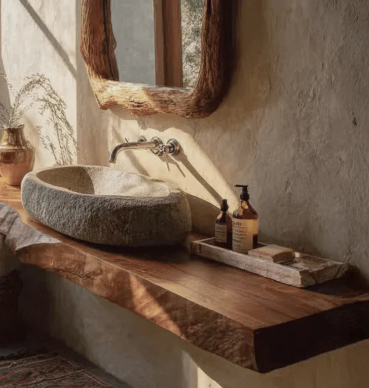 Rustic bathroom sink setup with stone basin, wooden countertop, natural light, and vintage soap dispensers