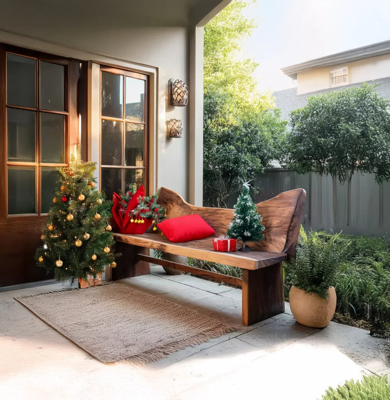 Cozy porch with wooden bench decorated with red pillows, miniature Christmas tree, and festive ornaments