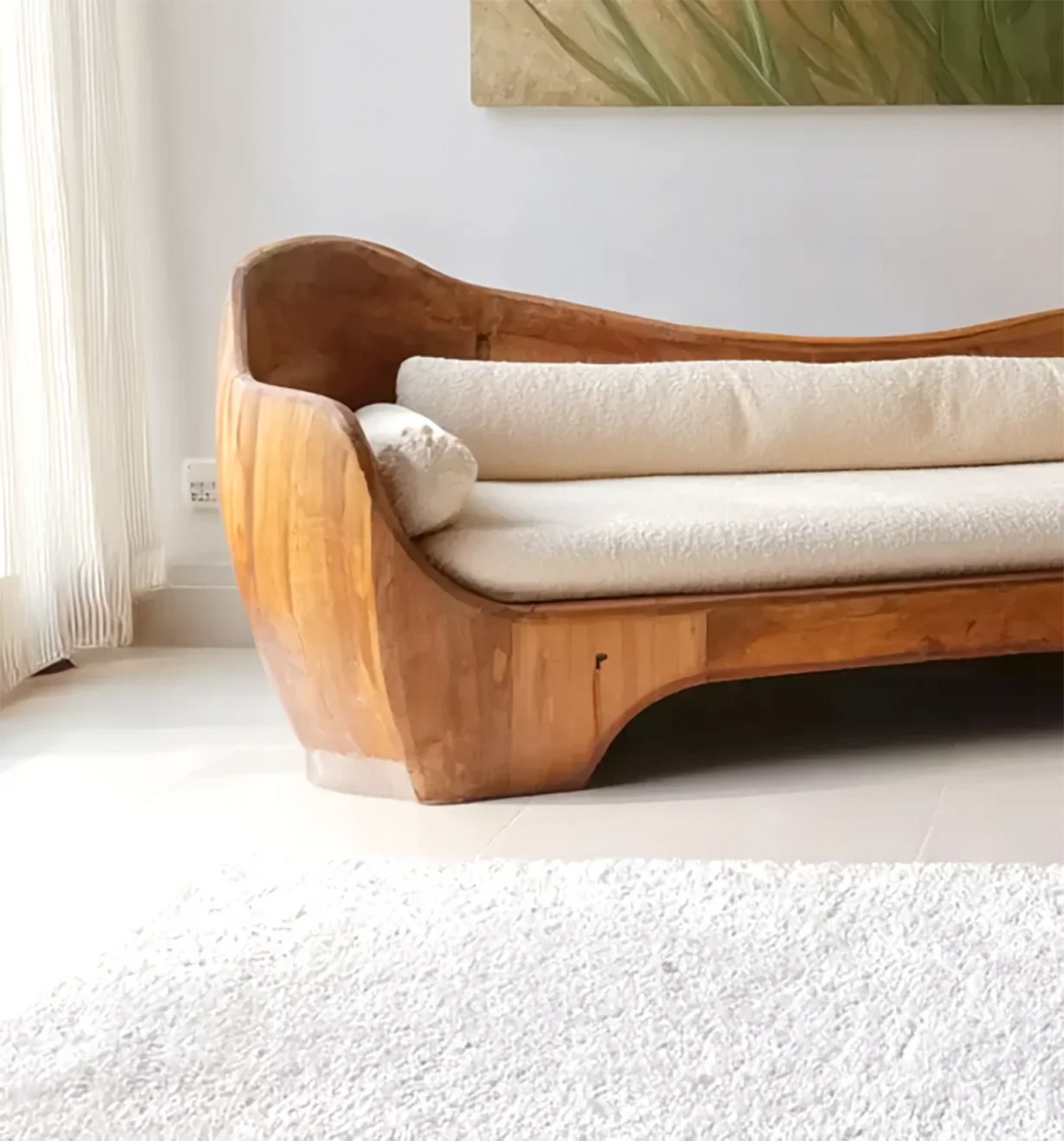 Modern wooden sofa with beige cushions in bright living room with white curtains and rug
