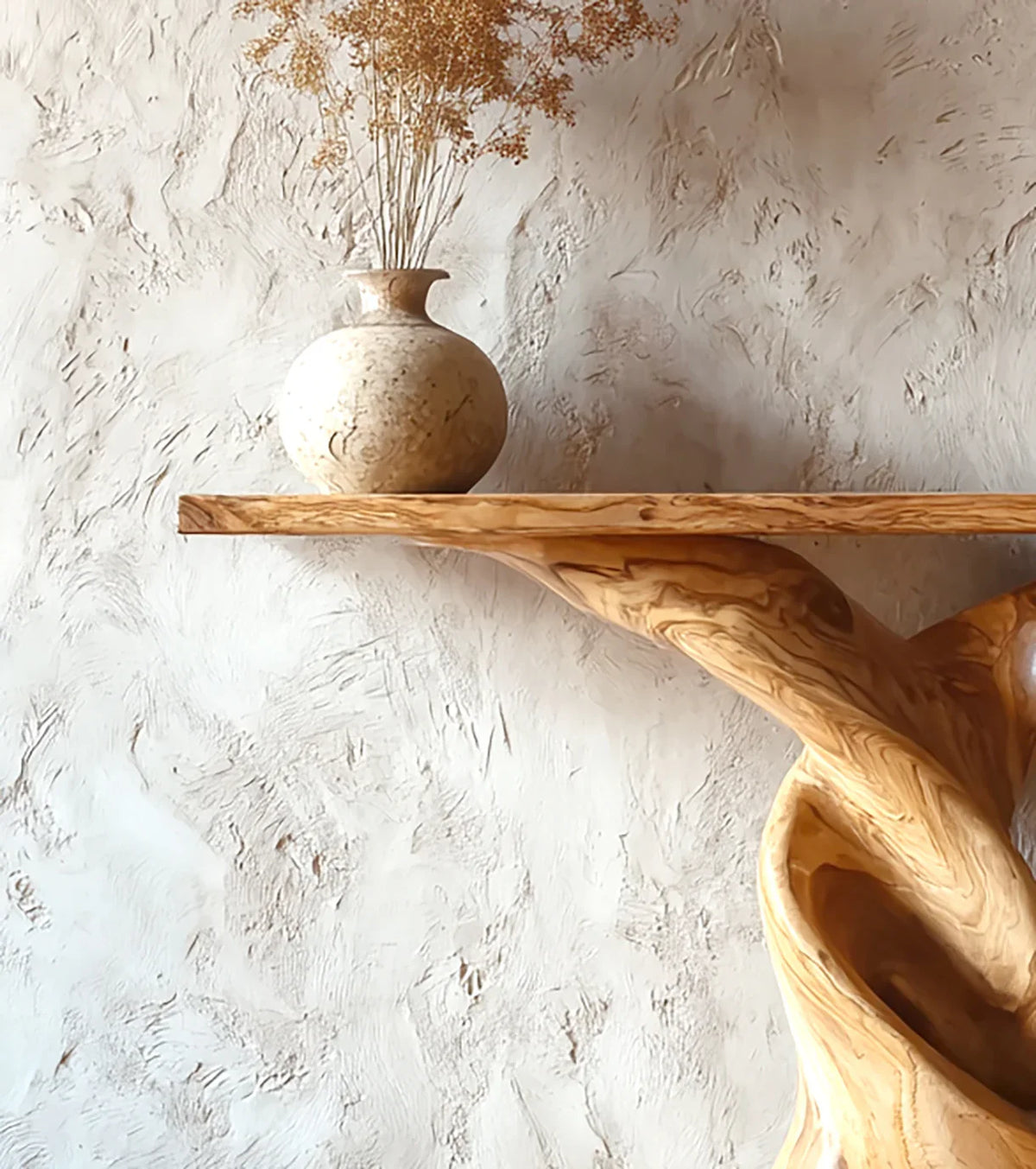 Rustic wooden shelf with a round beige vase holding dried flowers against textured plaster wall