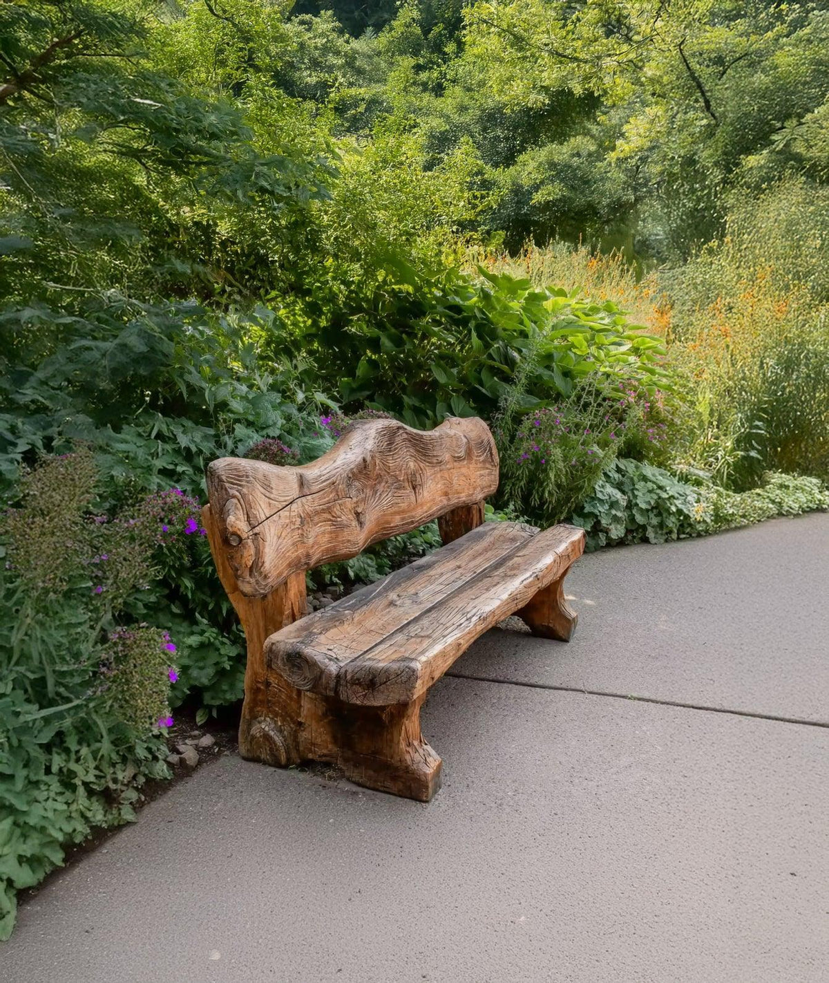 Handcrafted wooden bench on garden path surrounded by green plants and colorful flowers