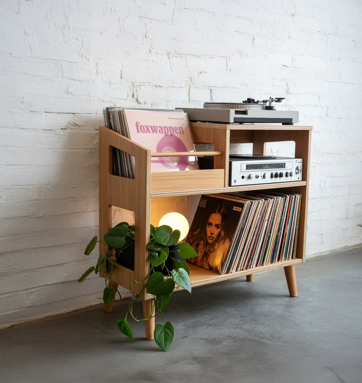 Modern wooden record player stand with vinyl records, turntable, amplifier, and potted plant