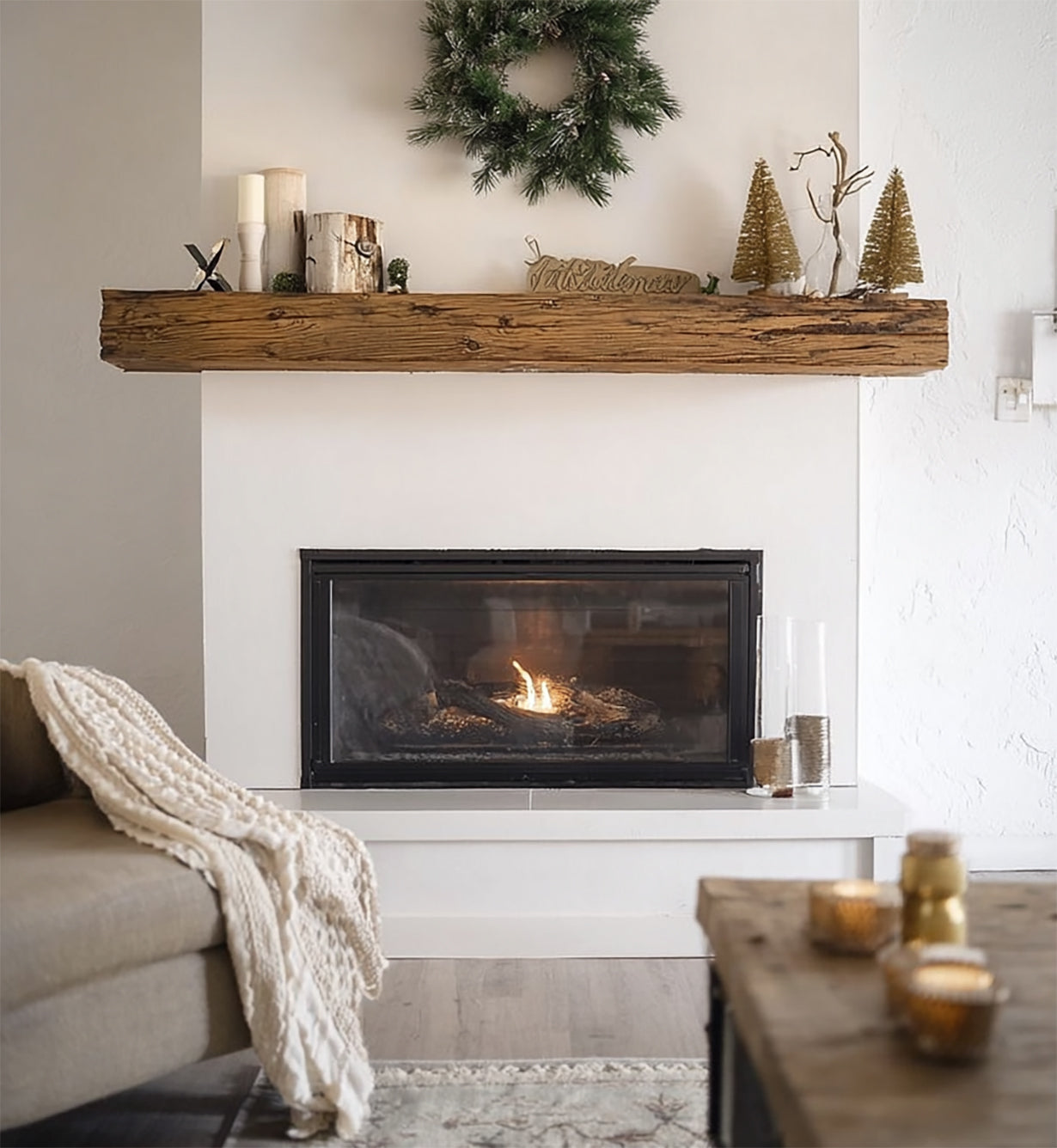 Cozy modern fireplace with wooden mantel decorated with wreath, candles, and Christmas trees