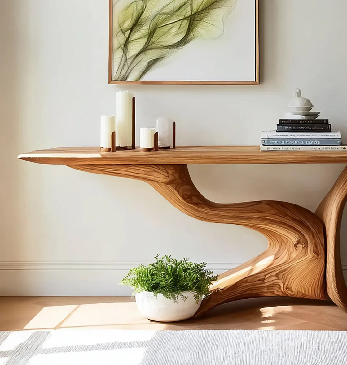 Live edge solid wood console table with sculptural base, candles, books, and potted plant