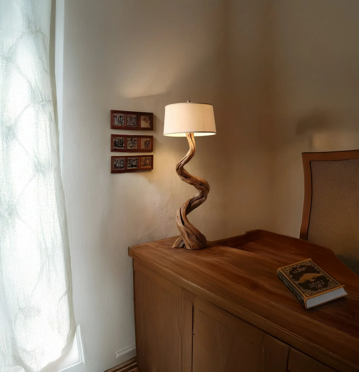 Rustic wooden lamp with twisted base on wooden desk next to a book and beige chair