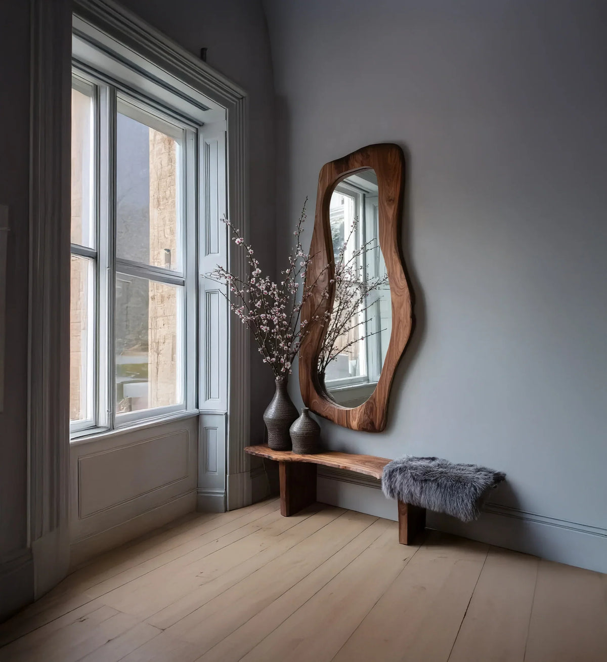 Live edge wood bench with vases and wall mirror in a bright, modern entryway