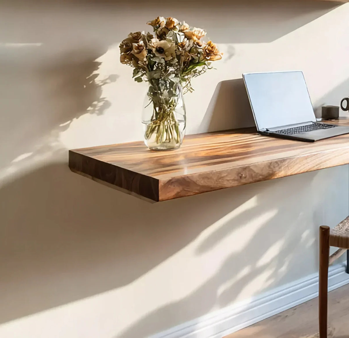 Floating solid wood desk with natural live edge, laptop, and vase of flowers in sunlight