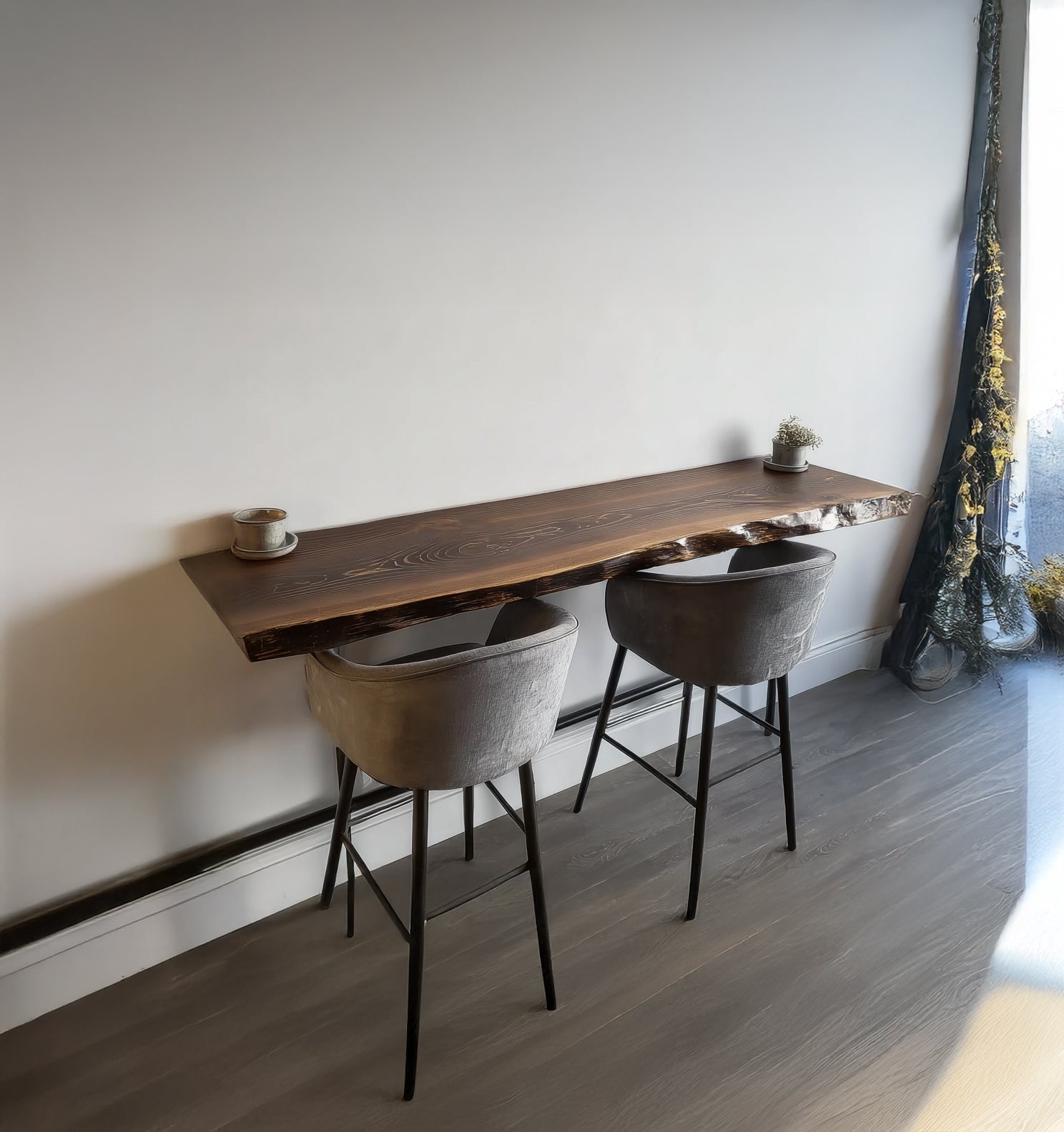Modern wooden bar counter with live edge and two grey velvet bar stools in a minimal room
