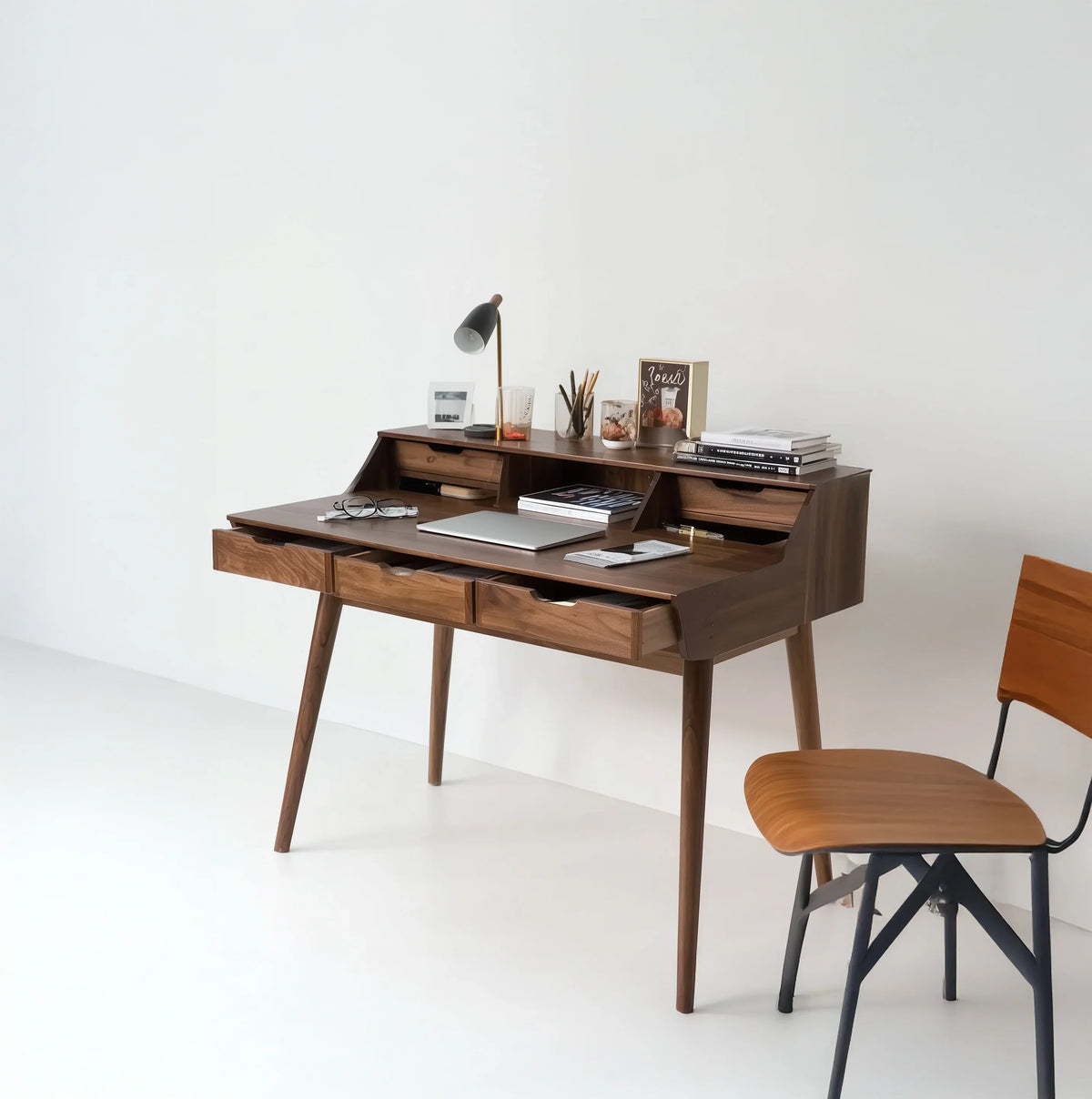 Modern solid wood writing desk with drawers, books, and chair in minimal home office
