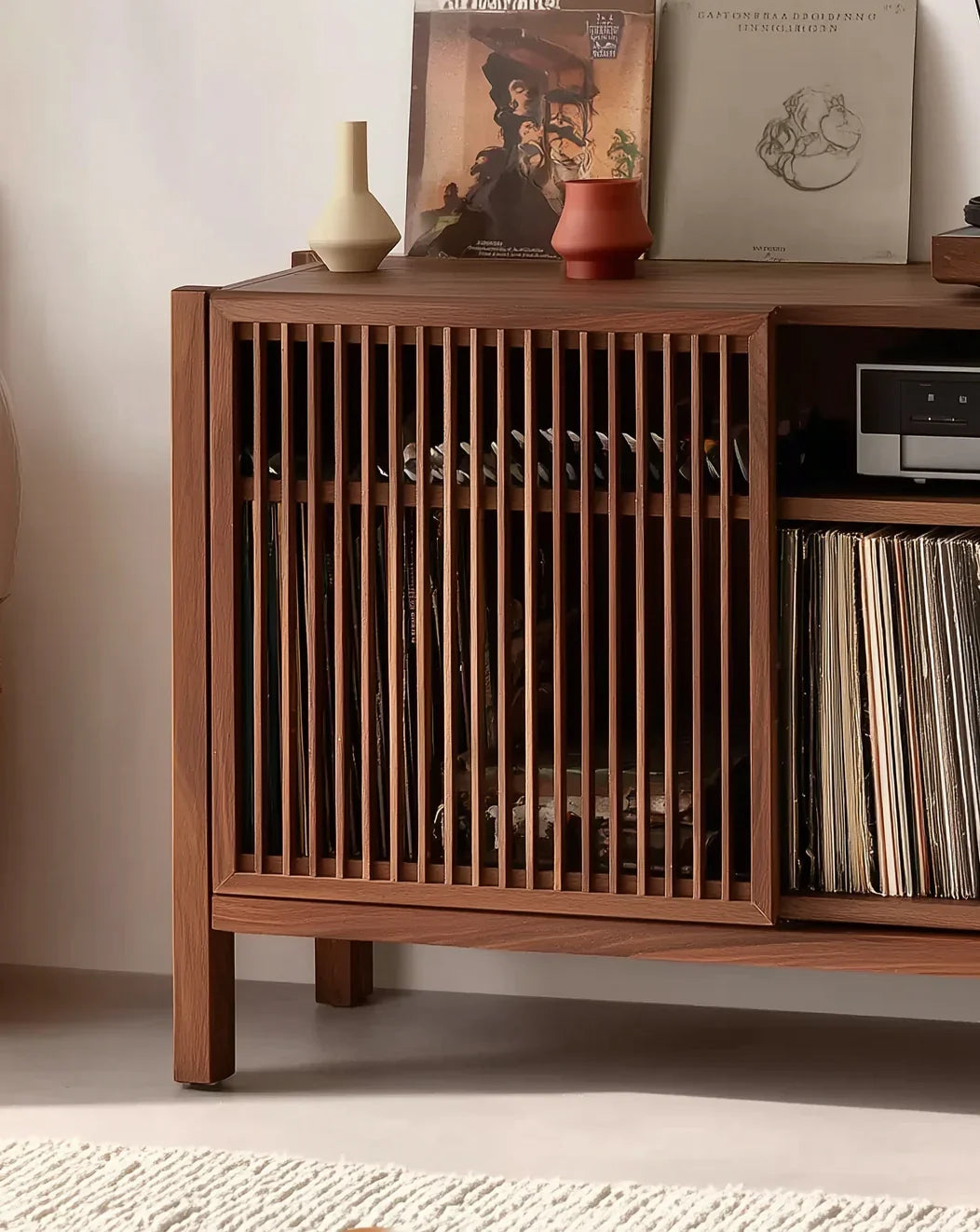 Solid wood slatted cabinet with vinyl records, minimalist vases, and modern decor.
