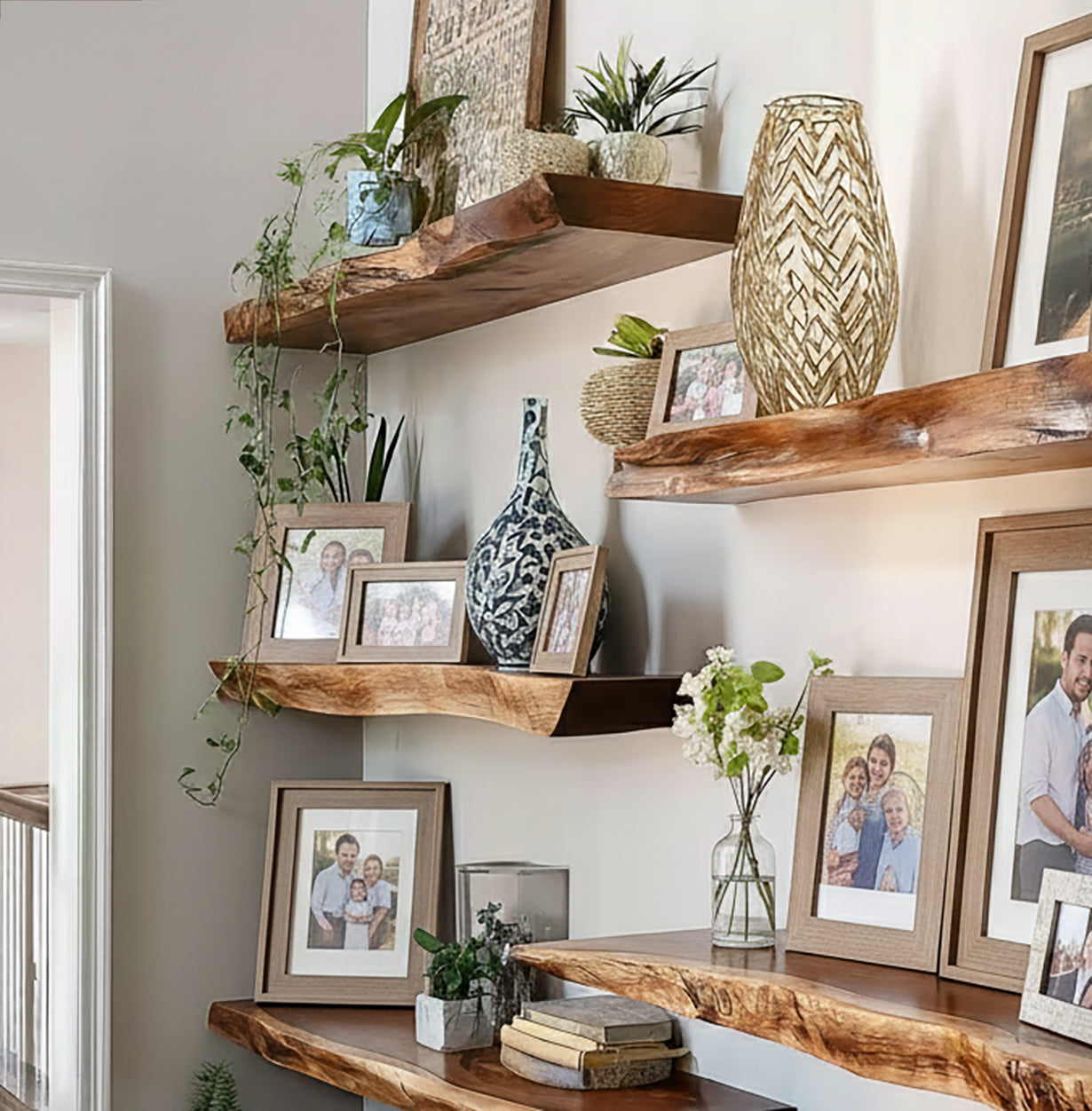 Rustic wooden floating shelves decorated with family photos, plants, vases, and books in a cozy home setting
